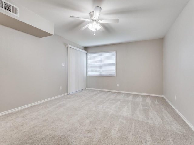 carpeted empty room featuring visible vents, baseboards, and a ceiling fan