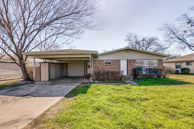 view of front of property featuring a front lawn, fence, concrete driveway, an attached carport, and brick siding