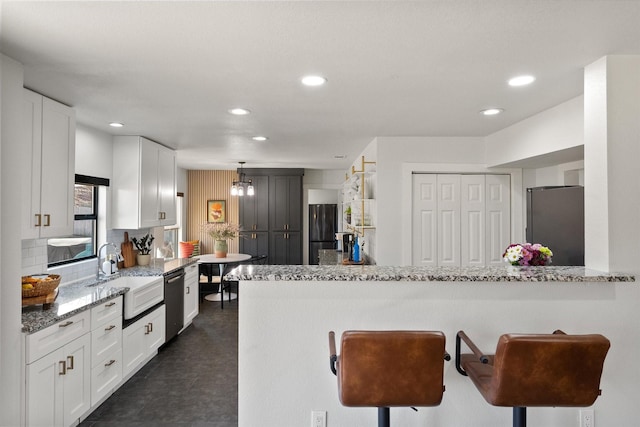 kitchen with a sink, stainless steel appliances, light stone counters, and white cabinets