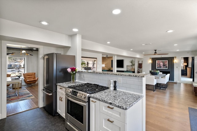 kitchen featuring light stone counters, stainless steel appliances, open floor plan, white cabinetry, and tasteful backsplash