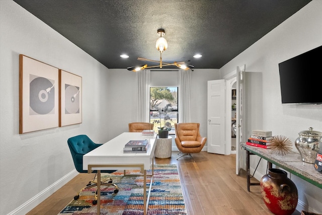 dining space featuring a textured ceiling, baseboards, and wood finished floors