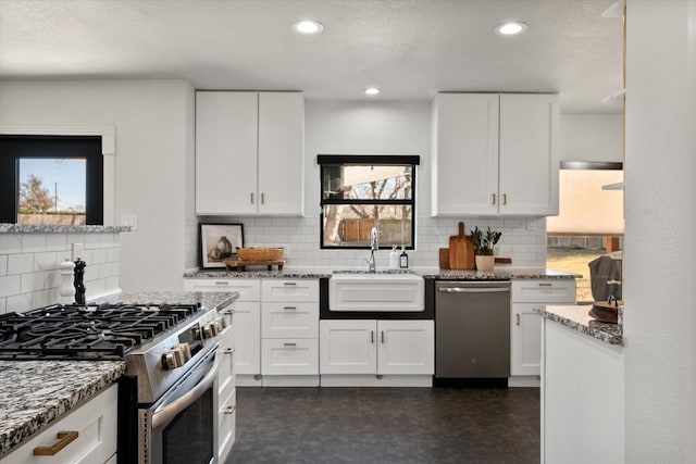 kitchen with light stone counters, white cabinets, appliances with stainless steel finishes, and a sink