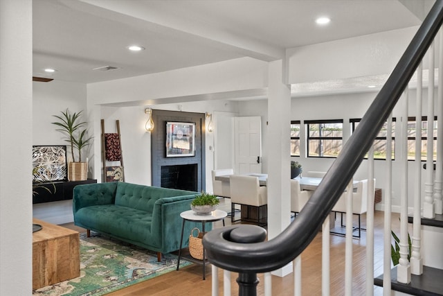 living room featuring stairway, recessed lighting, a brick fireplace, and wood finished floors