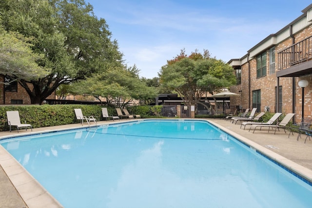 community pool with a patio and fence