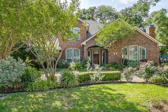 view of front of property featuring a front lawn, brick siding, and a chimney