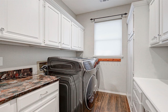 washroom featuring visible vents, dark wood-style floors, washing machine and dryer, cabinet space, and baseboards