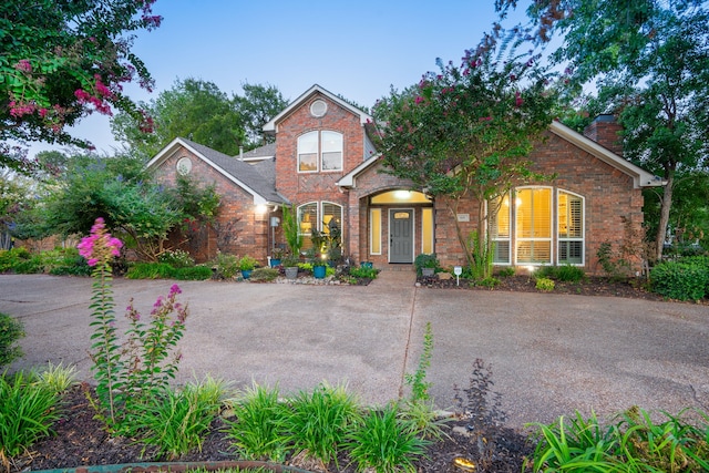 traditional home with concrete driveway, brick siding, and a chimney