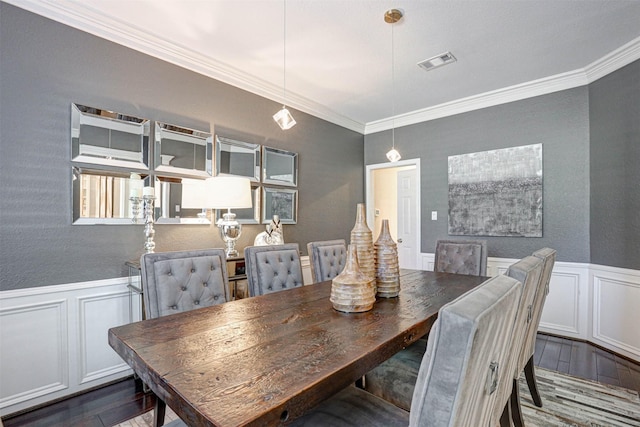 dining area with visible vents, a wainscoted wall, wood finished floors, and crown molding