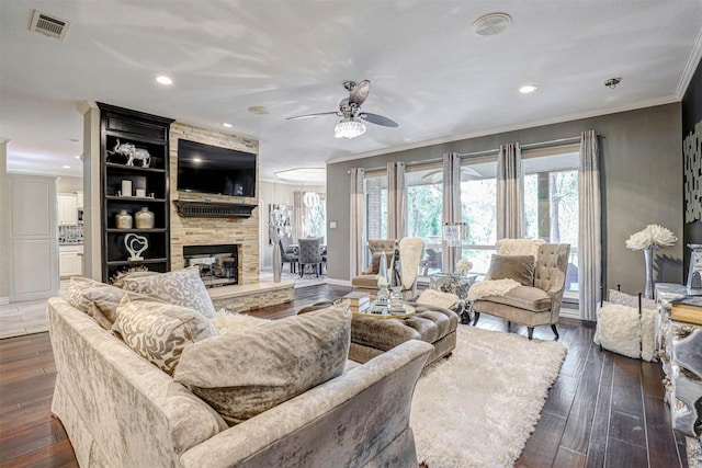 living room with dark wood-type flooring, a large fireplace, visible vents, and ornamental molding