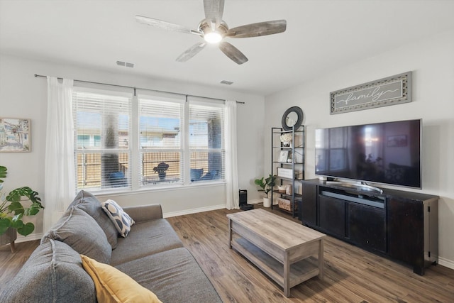 living room with visible vents, baseboards, wood finished floors, and a ceiling fan