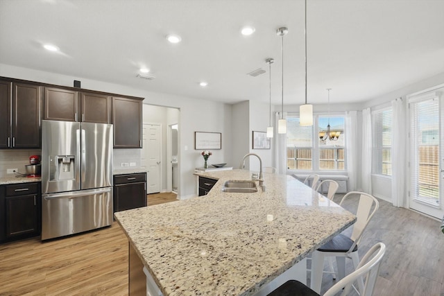 kitchen featuring backsplash, a breakfast bar, light wood-style floors, stainless steel fridge, and a sink