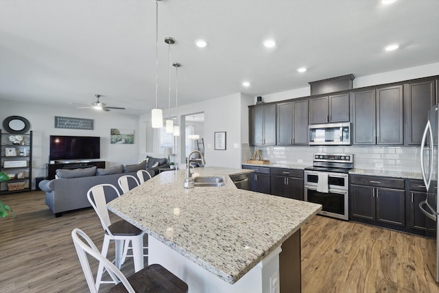 kitchen with backsplash, light stone countertops, a breakfast bar, appliances with stainless steel finishes, and a sink