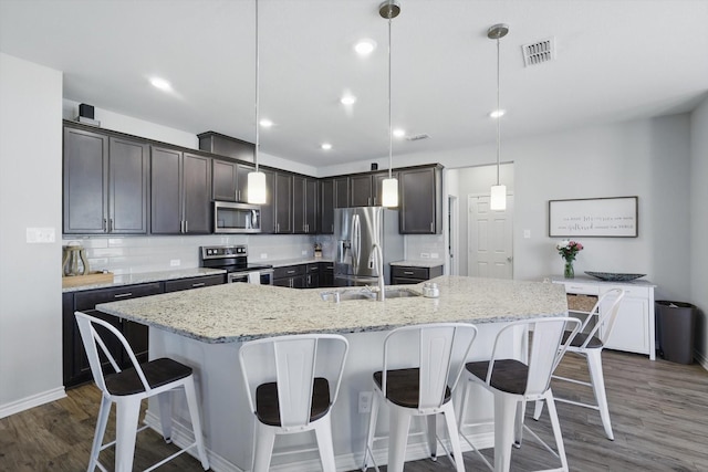 kitchen with visible vents, dark wood-type flooring, a spacious island, appliances with stainless steel finishes, and decorative backsplash