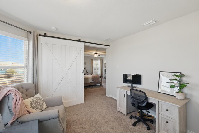 office space featuring baseboards, visible vents, a barn door, and light carpet