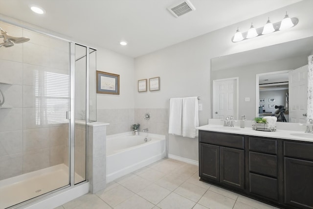 bathroom with tile patterned floors, a stall shower, a garden tub, and a sink