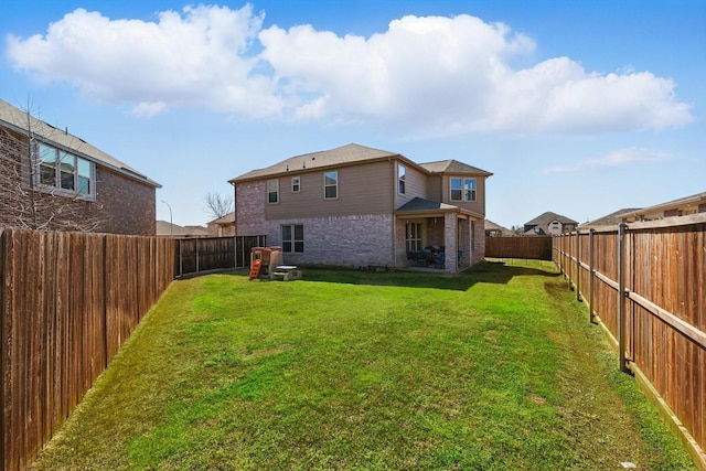 back of house with a lawn, a fenced backyard, and brick siding