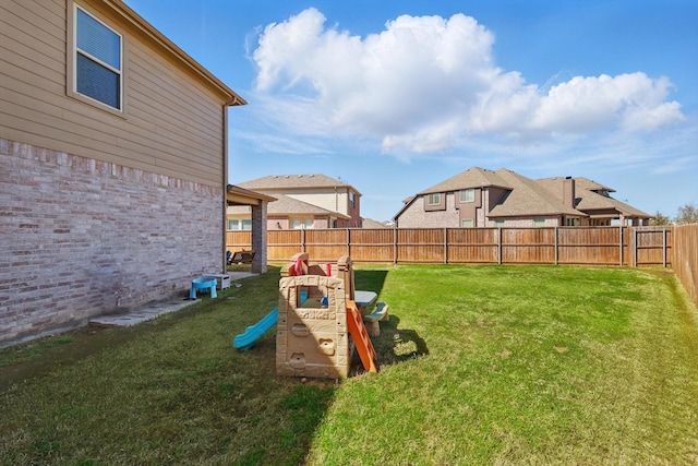 view of yard featuring a residential view, a fenced backyard, and a playground