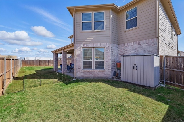 rear view of house with an outbuilding, a yard, a fenced backyard, and brick siding