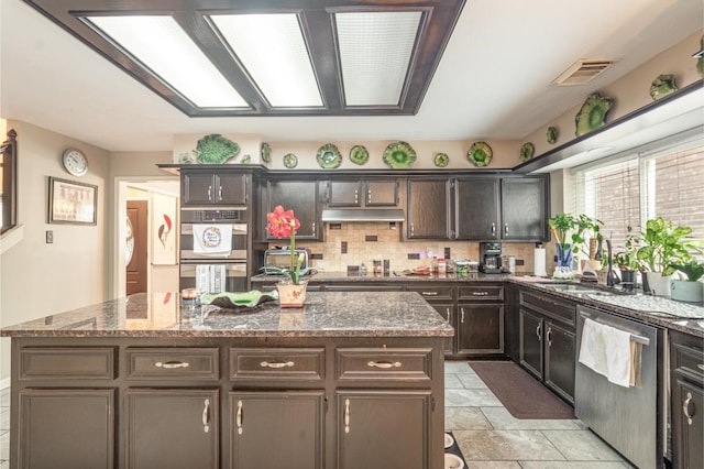 kitchen featuring visible vents, stainless steel appliances, under cabinet range hood, backsplash, and a center island