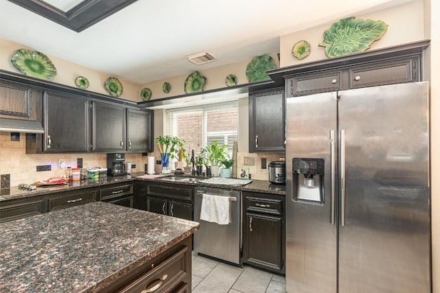 kitchen featuring visible vents, dark stone countertops, stainless steel appliances, light tile patterned floors, and decorative backsplash