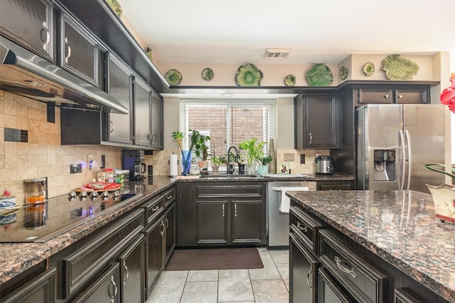 kitchen with visible vents, a sink, backsplash, stainless steel appliances, and exhaust hood