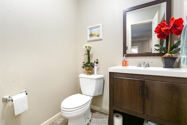 half bath with toilet, vanity, and baseboards