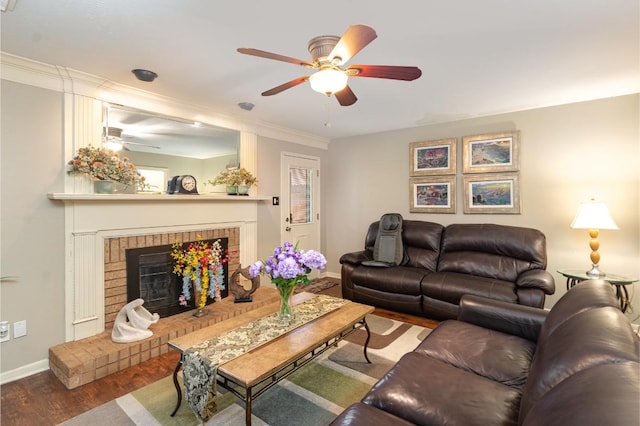 living room with ceiling fan, baseboards, ornamental molding, a fireplace, and wood finished floors