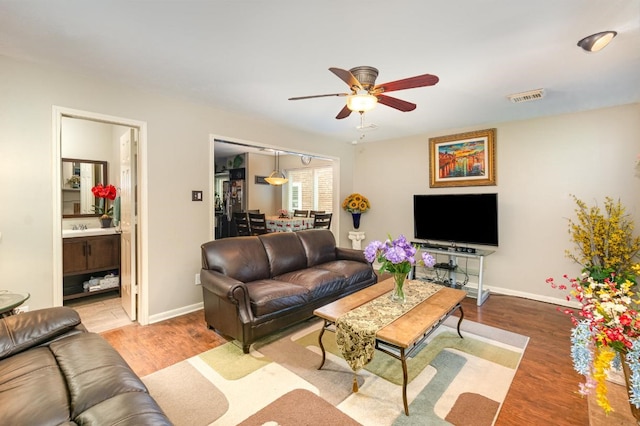 living room featuring wood finished floors, visible vents, and baseboards