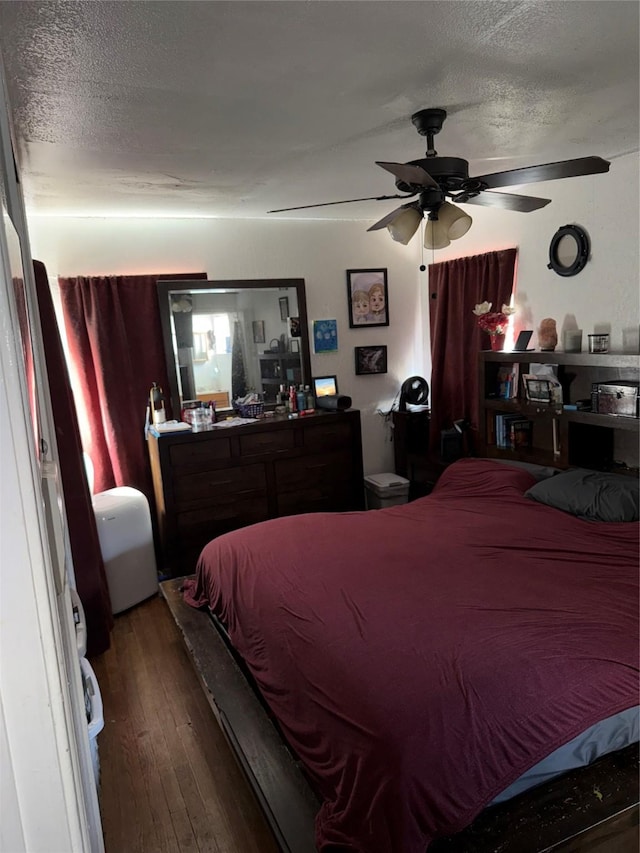 bedroom with a textured ceiling, hardwood / wood-style floors, and a ceiling fan