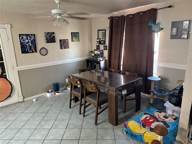 dining room with baseboards, a textured ceiling, light tile patterned flooring, and a ceiling fan