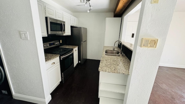 kitchen with baseboards, a sink, dark wood-type flooring, white cabinets, and appliances with stainless steel finishes