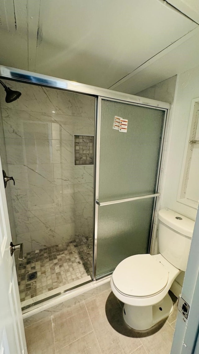 bathroom featuring tile patterned floors, a stall shower, and toilet