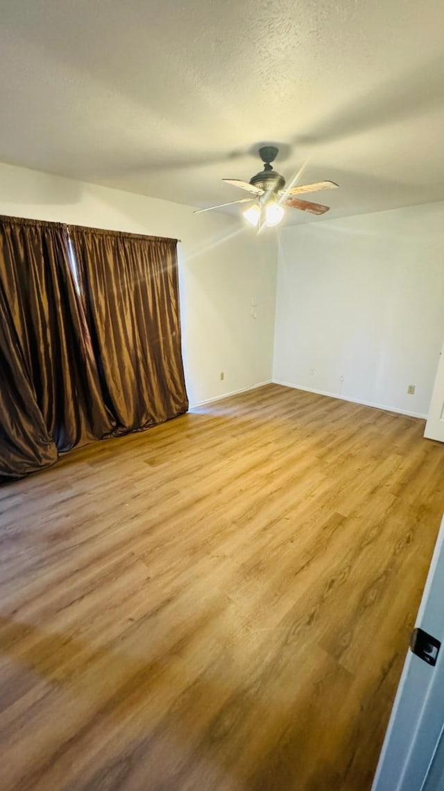 unfurnished room with light wood-type flooring, a textured ceiling, and ceiling fan