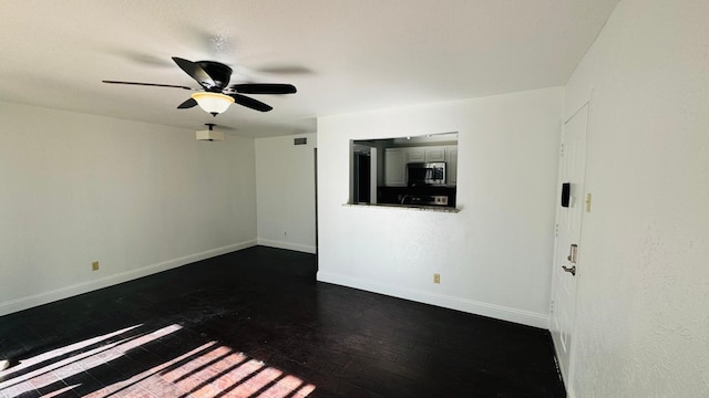 unfurnished room featuring ceiling fan, dark wood-type flooring, and baseboards