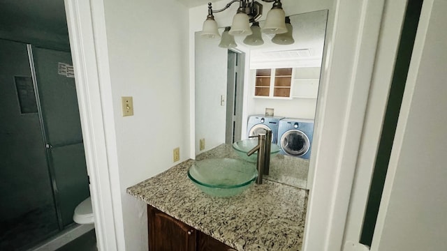 bathroom featuring vanity, toilet, separate washer and dryer, and a chandelier