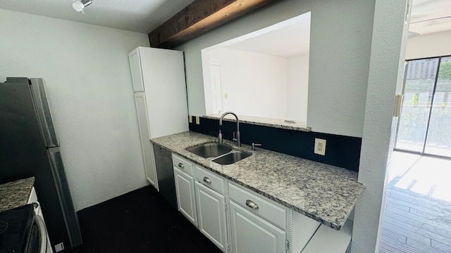 kitchen with white cabinetry, freestanding refrigerator, black dishwasher, and a sink