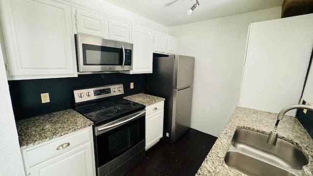 kitchen featuring white cabinetry, light stone counters, appliances with stainless steel finishes, and a sink