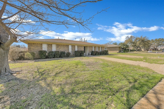 single story home with brick siding, concrete driveway, and a front yard