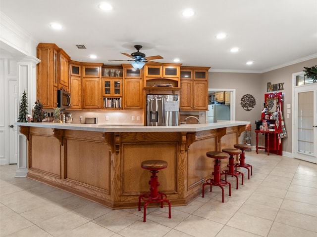 kitchen featuring crown molding, visible vents, appliances with stainless steel finishes, and brown cabinets