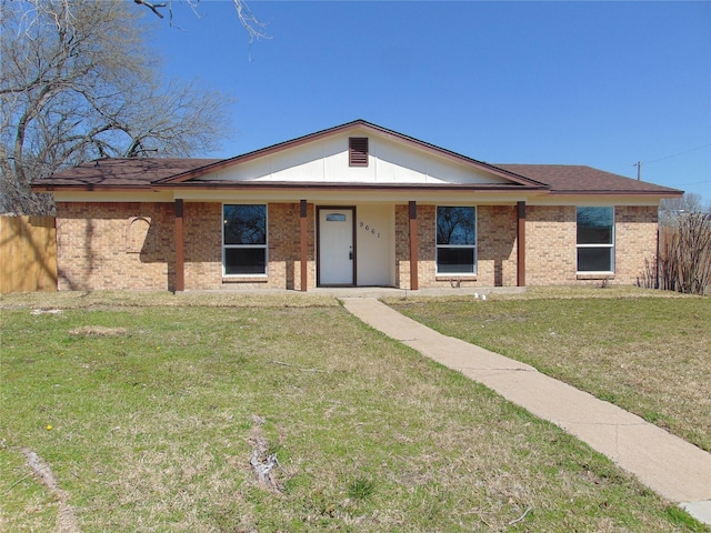 view of front of home featuring brick siding, covered porch, a front lawn, and fence