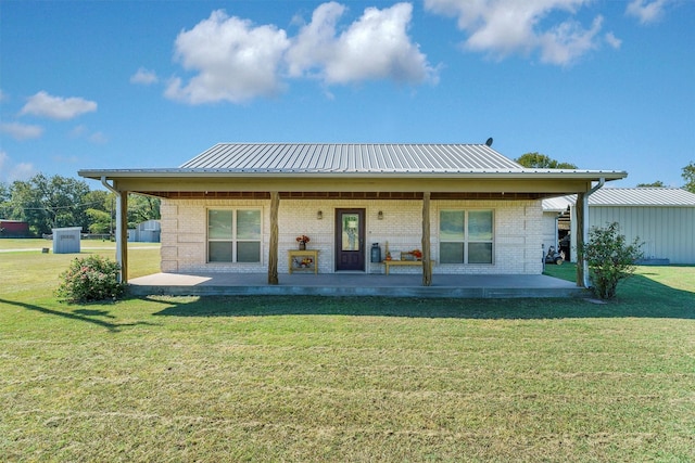 back of property featuring a lawn, brick siding, and metal roof