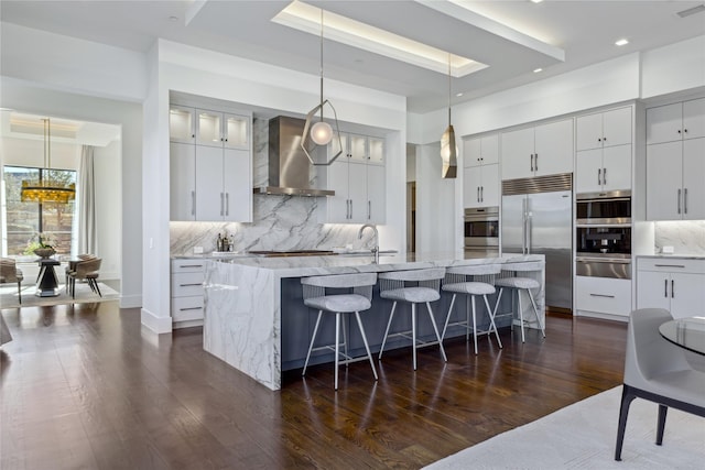 804 Kimball Ct, Allen, TX 75013 - kitchen with wall chimney range hood, stainless steel appliances, a warming drawer, a large island with sink, and backsplash