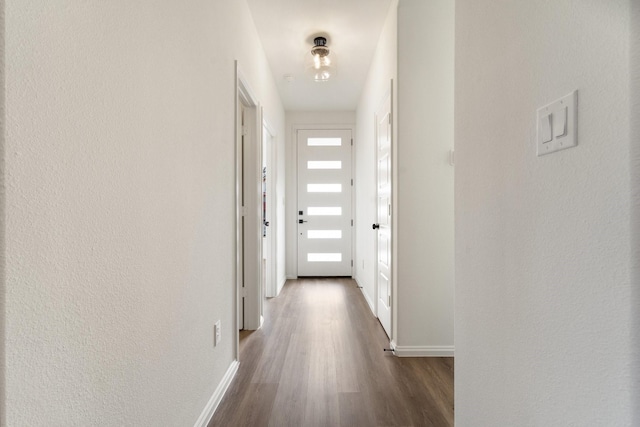 hallway with a wealth of natural light, baseboards, dark wood-type flooring, and a textured wall