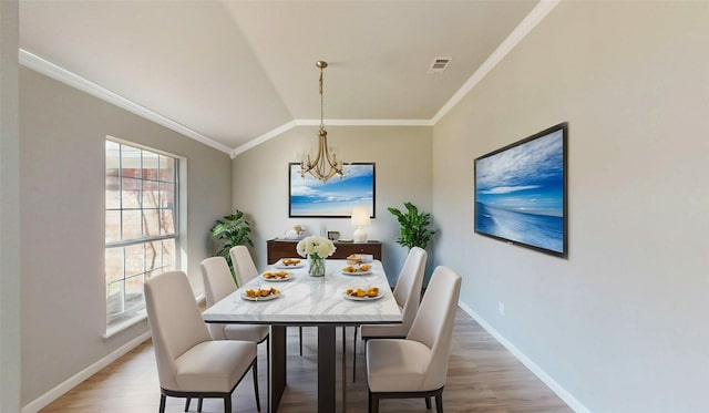 dining area featuring light wood-type flooring, lofted ceiling, crown molding, baseboards, and a chandelier