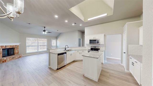 kitchen featuring visible vents, a brick fireplace, open floor plan, stainless steel appliances, and a sink