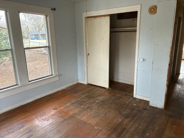 unfurnished bedroom featuring a closet, baseboards, and dark wood-style flooring