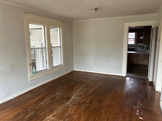 spare room featuring crown molding, baseboards, and wood-type flooring