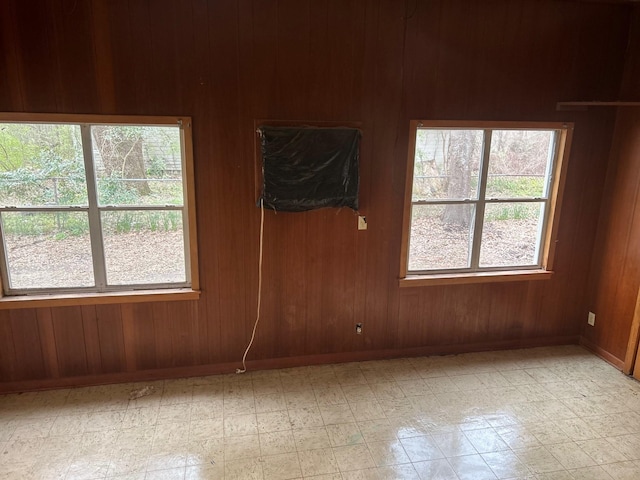 empty room with wooden walls, light floors, and baseboards