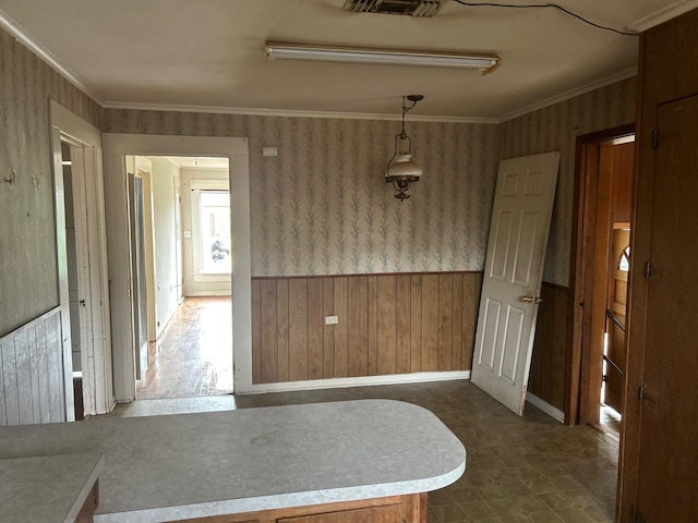 empty room featuring visible vents, wainscoting, wallpapered walls, and ornamental molding