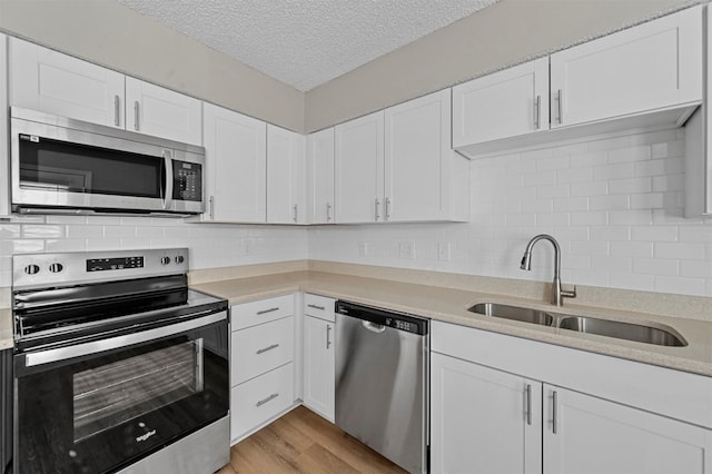 kitchen featuring white cabinets, appliances with stainless steel finishes, light countertops, and a sink